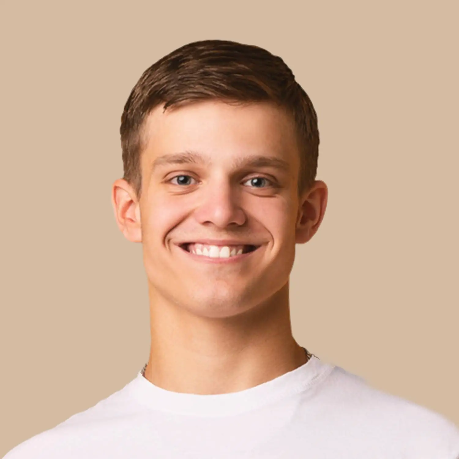 A young man with short brown hair, wearing a white t-shirt, smiles at the camera against a plain beige background. Fiamma Sun Valley | Italian