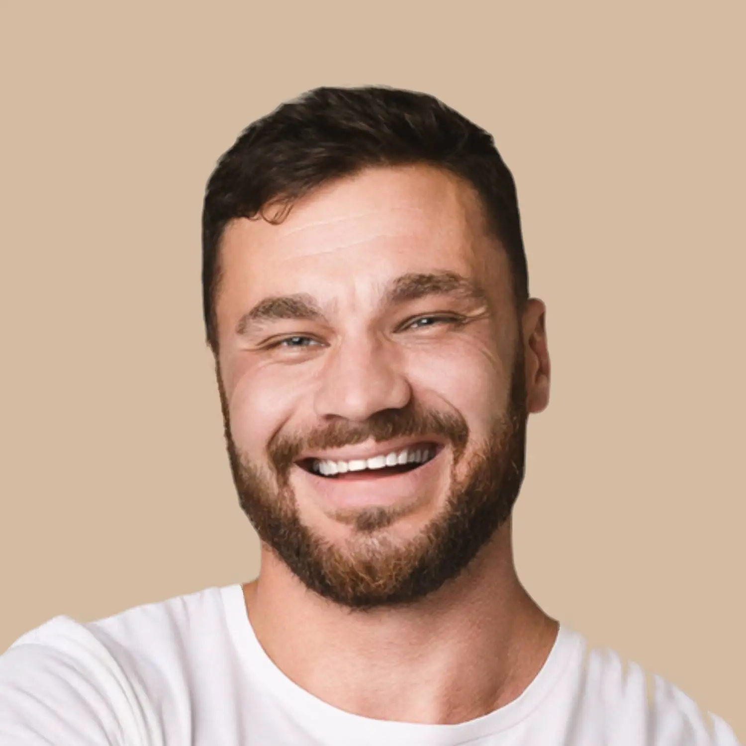 A bearded man with short dark hair smiles broadly while wearing a white t-shirt, posed against a plain beige background. Fiamma Sun Valley | Italian
