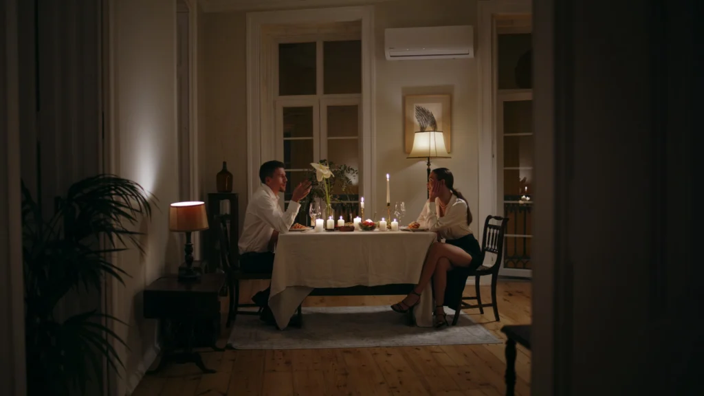 A man and woman sit at a candlelit dining table in a cozy, warmly lit room, enjoying a meal and conversation in an intimate setting. Fiamma Sun Valley | Italian